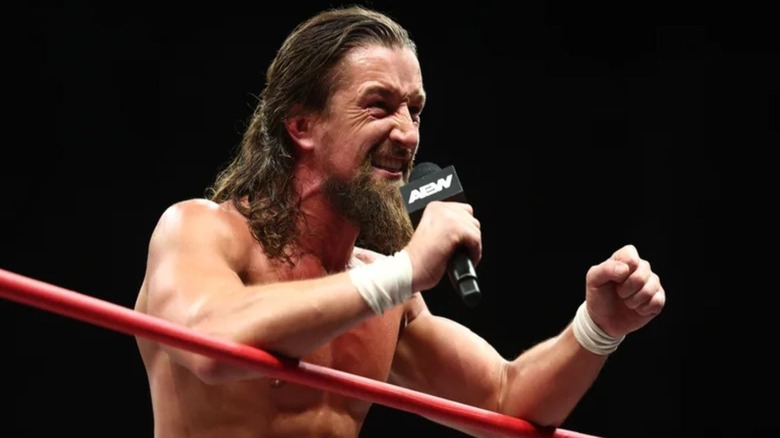Jay White leans over the ropes to a cut a promo on an opponent during an episode of AEW programming.